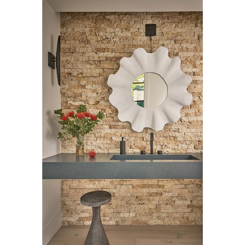 A round mirror in the floral shape frame fixed on the sink